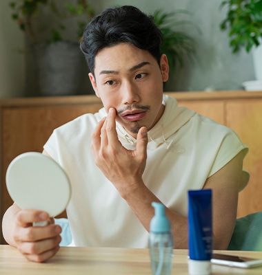 手鏡で肌の状態を確認する男性